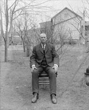 Man sitting in a chair outdoors ca.  between 1910 and 1935