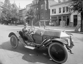 A man driving an early 20th century roadster car ca.  between 1910 and 1926