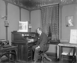 Raymond Dickey working at a desk ca.  between 1910 and 1925