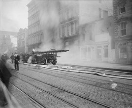 Early 20th century horse drawn firetruck at the scene of a fire ca.  between 1910 and 1925