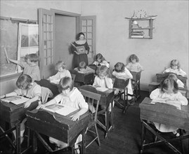 Young school children sitting in desks reading at the Maret French School, [Washington, D.C.]. ca.  between 1910 and 1920