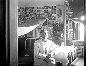 Young man in dormitory room ca.  between 1910 and 1920