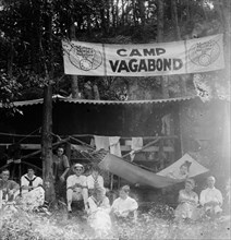 Summer camps: Group of campers sitting under a Camp Vagabond sign  ca.  between 1910 and 1935