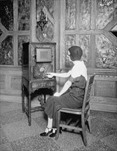 Woman tuning a radio between 1910 and 1935