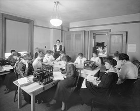 Office with women writing and using typewriters. ca.  between 1910 and 1920