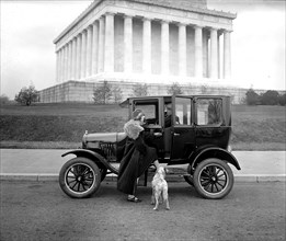 Ford Motor Company, sedan, man opening the door for a woman and her dog ca.  between 1910 and 1925