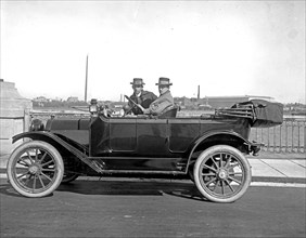 Two men driving a Briggs Detroiter automobile, [Washington Monument, Washington, D.C., in background] ca.  between 1910 and 1925