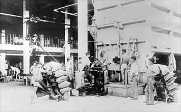 Filling, weighing and sewing sacks of raw sugar at Plantation mill, Hawaiian Islands ca. 1910 to 1920