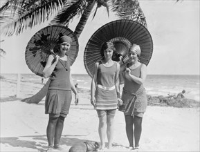 Three women on a beach with umbrellas in the early 20th century ca.  between 1910 and 1920