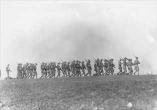 Soldiers marching with rifles in a field, probably a U.S. Army training exercise in the United States ca.  1917