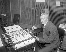 Man working in War Risk department at check writing machine ca. between 1909 and 1940