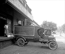 Man loading food onto a Ford Motor Company delivery truck ca.  between 1910 and 1926