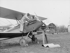 Men examining airplane engine ca. between 1909 and 1923