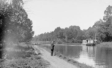 Man standing next to the C&O Canal, possibly taking a photo of a boat / Chesapeake & Ohio Canal ca. between 1909 and 1923