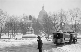 Man standing near the U.S. Capitol on a snowy day ca. between 1909 and 1923