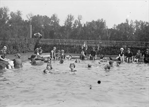 Teens enjoying a day of swimming at a municipal bathing beach / city swimming pool  ca. between 1909 and 1919
