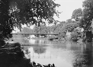 People walking across the Chain Bridge over the C&O Canal ca. between 1909 and 1923