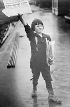 Young newsboy in Alaska selling newspapers ca. between 1909 and 1920