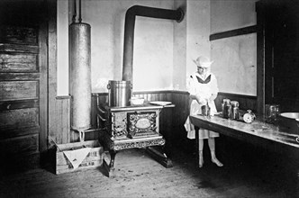 Woman preparing food in a Kitchen ca. between 1909 and 1923