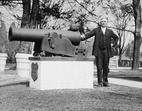 J.F. Schnell, Superintendent of  Battle Cemetery standing next to a cannon ca. between 1909 and 1919