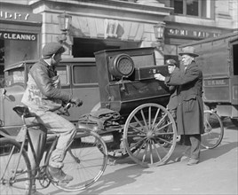 Street scene: newspaper delivery boy on a bicycle, man with cart near laundry ca. between 1909 and 1932