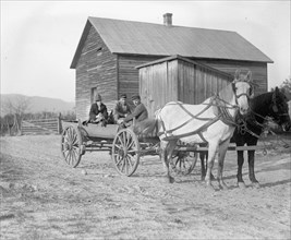 Three people in horse drawn wagon ca. between 1909 and 1932