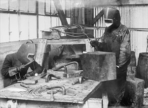 Workers cutting with acetylene flame, using masks & blue glass to protect the eyes ca. between 1909 and 1920