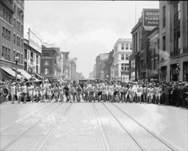 Street scene with runners at the start of a footrace ca. between 1909 and 1923