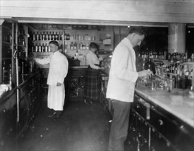 Pharmacists at People's Drug Store, 7th and E Streets, N.E., Washington, D.C., at counter preparing medications ca. between 1909 and 1932
