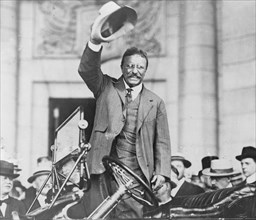 Theodore Roosevelt, three-quarter length portrait, standing up in car, waving hat ca. between 1909 and 1932