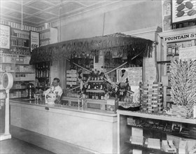 Interior of People's Drug Store, 7th and M Streets, Washington, D.C., with employee behind the counter of soda fountain ca. between 1909 and 1932