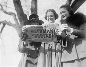 Peace demonstration, women holding newspaper with the headline, "Germany Surrenders!"  ca.  1918