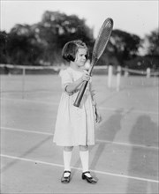Peggy Baker on tennis court, holding a tennis racquet  ca.  between 1918 and 1920