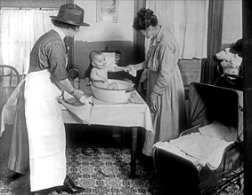 Child Welfare Bureau: Infant Welfare, Parent giving a child a bath ca.  between 1918 and 1928