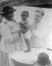 African American woman has her toddler examined by a doctor or nurse ca.  between 1918 and 1928
