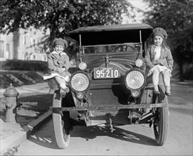 Children sitting on the fender of a car next to a fire hydrant ca.  between 1918 and 1920