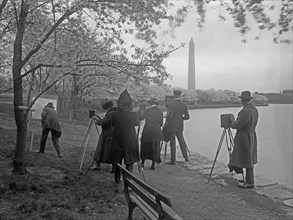 Photographers taking a photo of a man painting on a canvas, the Washington Monument in the background ca. [between 1909 and 1940]