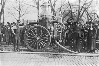 Early 20th century firemen stand next to fire engine ca. 1909