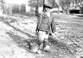 Young boy carrying a bucket of coal  ca. 1909