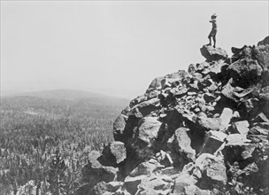 Man looking out from rocky cliff side in an unidentified national park ca. 1909