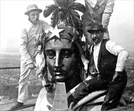 Three men with Statue of Freedom on top of the U.S. Capitol ca. 1909