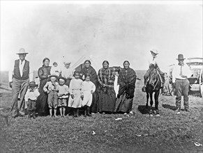 Group of Kickapoo Indians, standing outside tent, dressed in Euro-American clothing ca. 1909