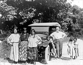 Gypsy women and children, and man with automobile ca. 1909