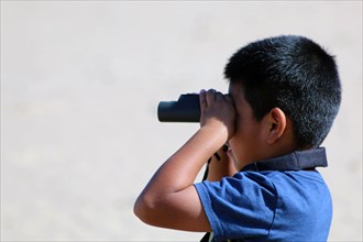 A second grader from Santa Rita Elementary School peers through binoculars to spot the western snowy plovers scurrying along the shoreline at Monterey State Beach ca. 1 April 2014