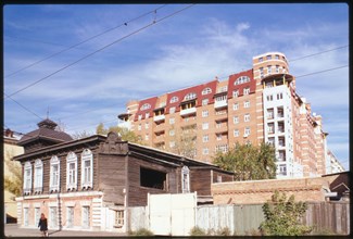 Log house, Marshal Zhukov Street #95 (around 1900), foreground, and in the background is a typical modern apartment building of the post Soviet period (late 1990s), Omsk, Russia 1999.