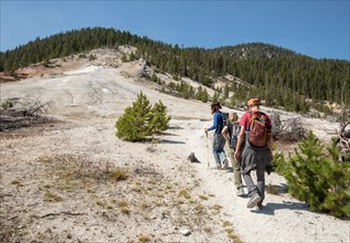 Hikers on a trail going uphill with hydrothermally altered rock all around. Seven Mile Hole Trail in Yellowstone National Park; Date: 11 September 2017