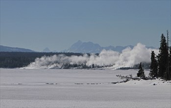 View across Yellowstone Lake to West Thumb Geyser Basin in Yellowstone National Park.  Grand Teton Mountain Range is 50 miles in the distance; Date: 17 January 2014