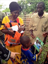 The leader of a community nutrition group in the mountains of Tanzania shares nutrition cards with her grandson ca. 4 March 2014