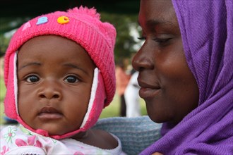 A woman in a purple head scarf looks lovingly at her daughter Angel (Tanzania) ca. 4 March 2014