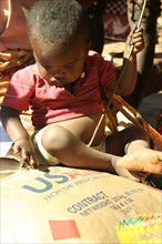 A toddler plays with a bag of food in Madagascar ca. 24 July 2010